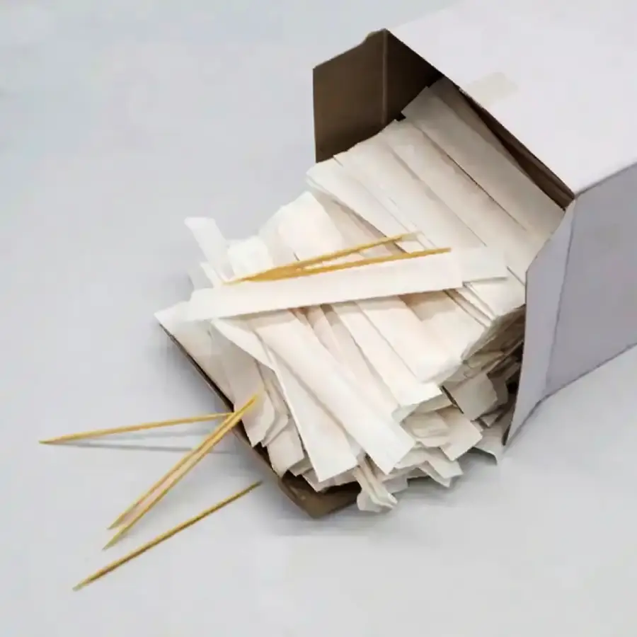 A box of individually wrapped wooden toothpicks, with several toothpicks and wrappers spilling out onto a white surface.
