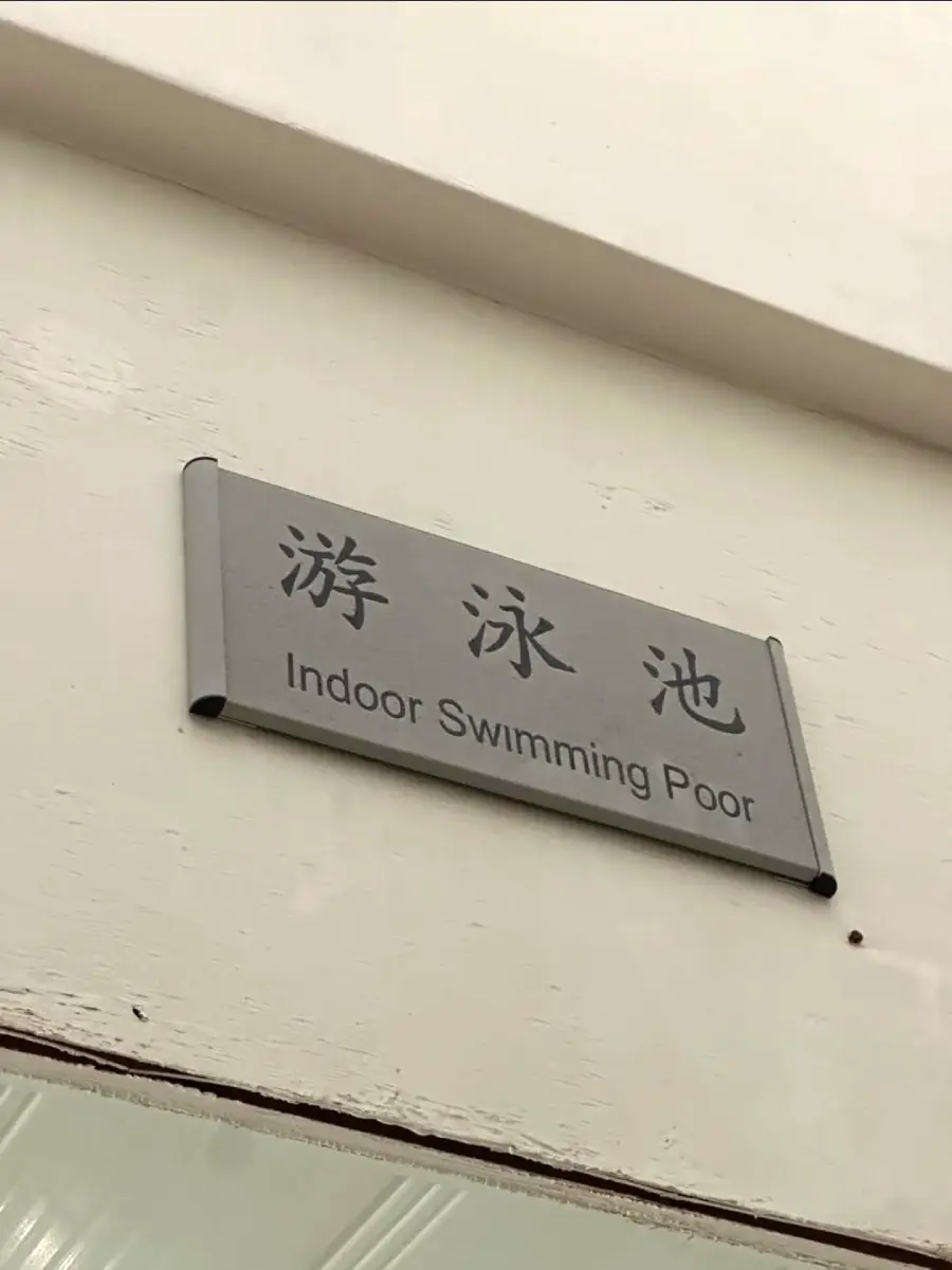 A sign with Chinese characters and English text reads “Indoor Swimming Poor” instead of “Indoor Swimming Pool.” The sign is mounted above a doorway.
