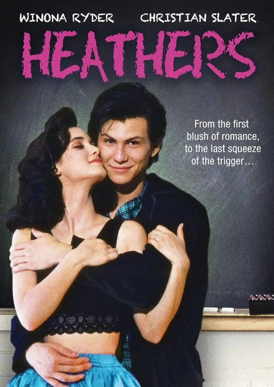 Movie poster for "Heathers" shows a young woman embracing a young man in front of a chalkboard. Bold pink text displays the title. Tagline reads: "From the first blush of romance, to the last squeeze of the trigger...