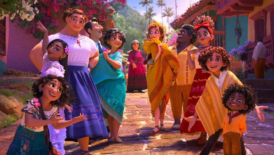 A colorful animated group of people stand and smile together on a sunlit cobblestone street, surrounded by vibrant houses and lush greenery. They appear joyful, with some gesturing and interacting warmly.