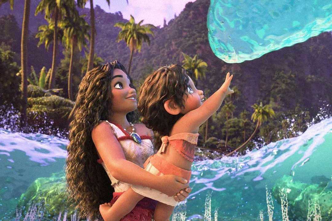 Animated scene of a girl holding up a young child toward a wave shaped like a hand. They are smiling, surrounded by water, palm trees, and lush mountains in the background.