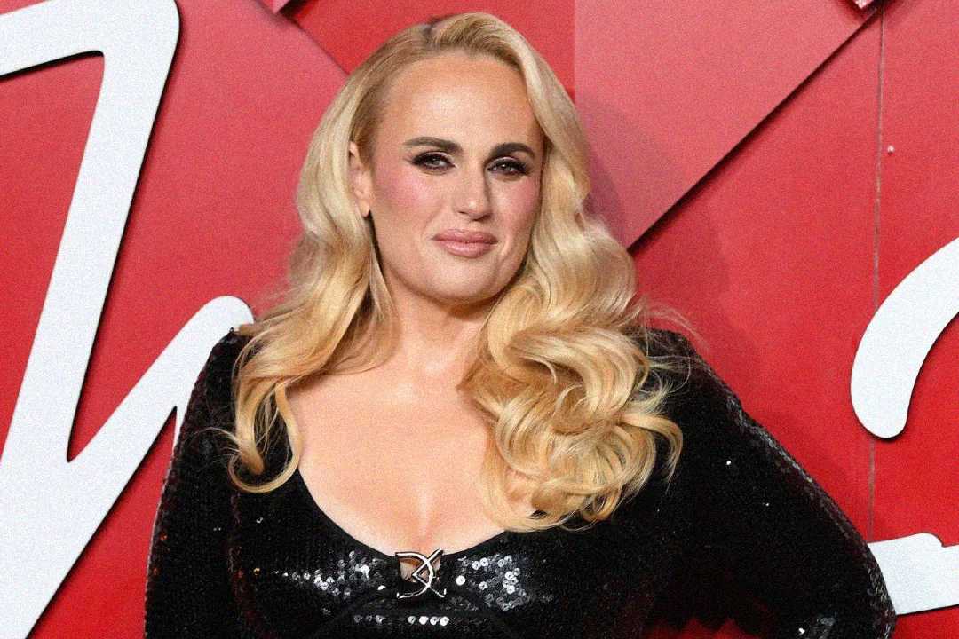A woman with long, wavy blonde hair in a sparkling black dress poses in front of a red background with large white lettering.