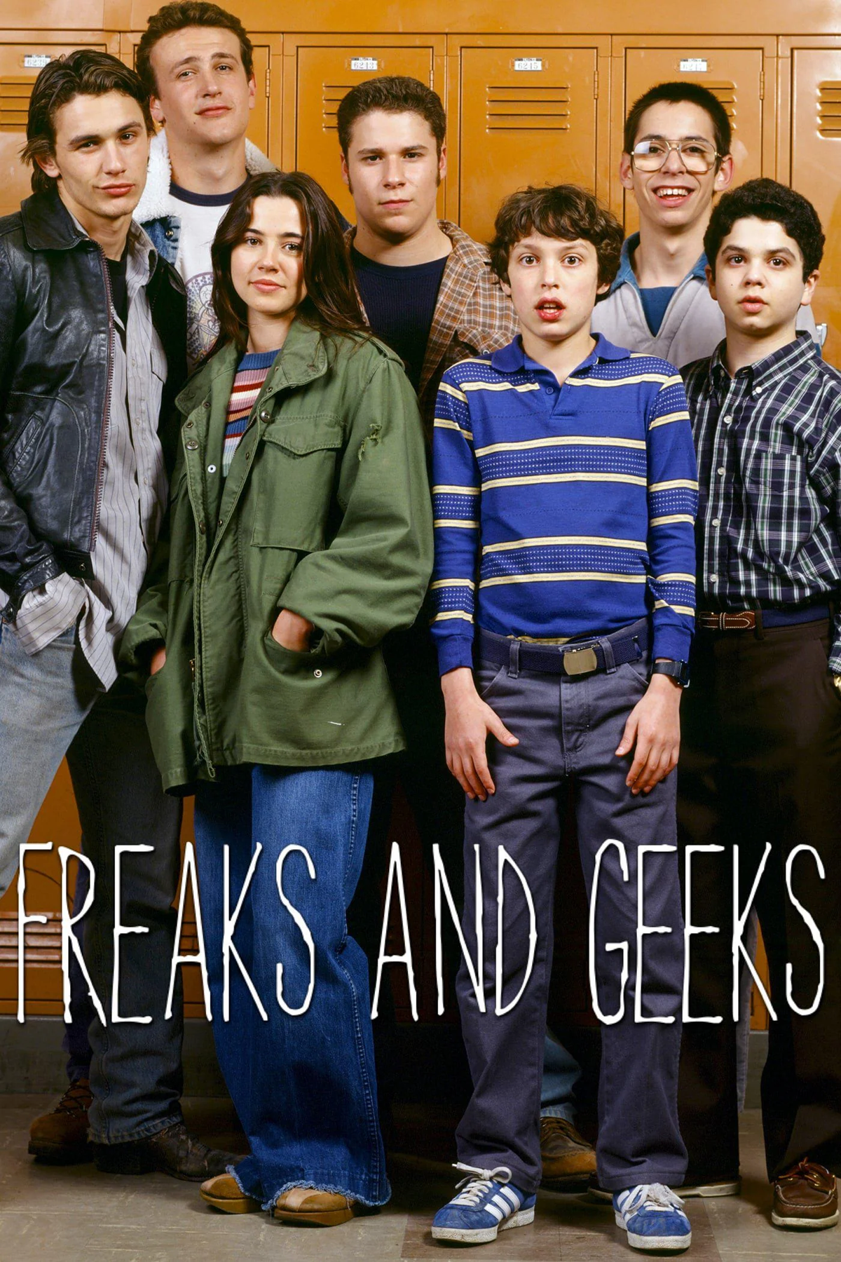 TV. Seven teenagers stand in front of orange lockers, dressed in casual 1980s clothing. Four are standing in back and three in front. The words “Freaks and Geeks” appear at the bottom over their legs.