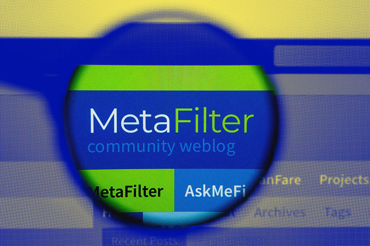 A magnifying glass focuses on the MetaFilter website logo, highlighting the words “MetaFilter community weblog” on a computer screen, with blurred website contents in the background.