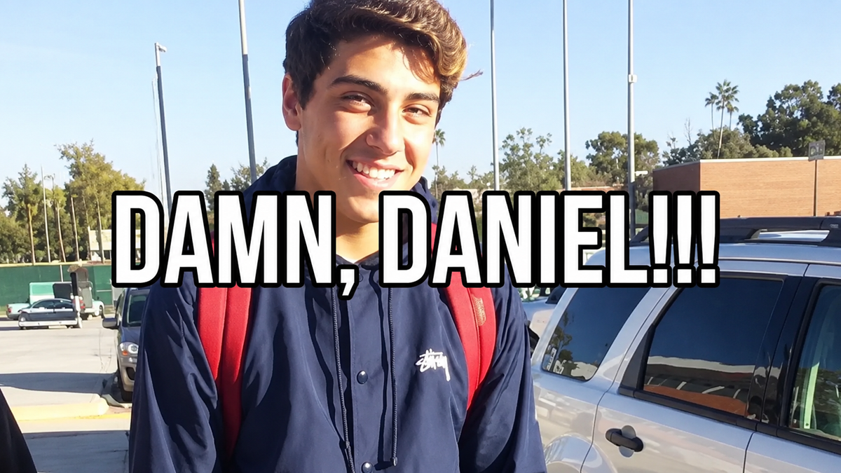 A young man with a red backpack smiles outdoors. Large bold text across the image reads, “DAMN, DANIEL!!!” Trees, cars, and a building are visible in the background under a clear sky.