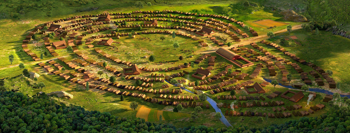 Aerial view of a reconstructed ancient settlement with concentric circular rows of wooden houses, surrounded by green fields, small streams, and forests.