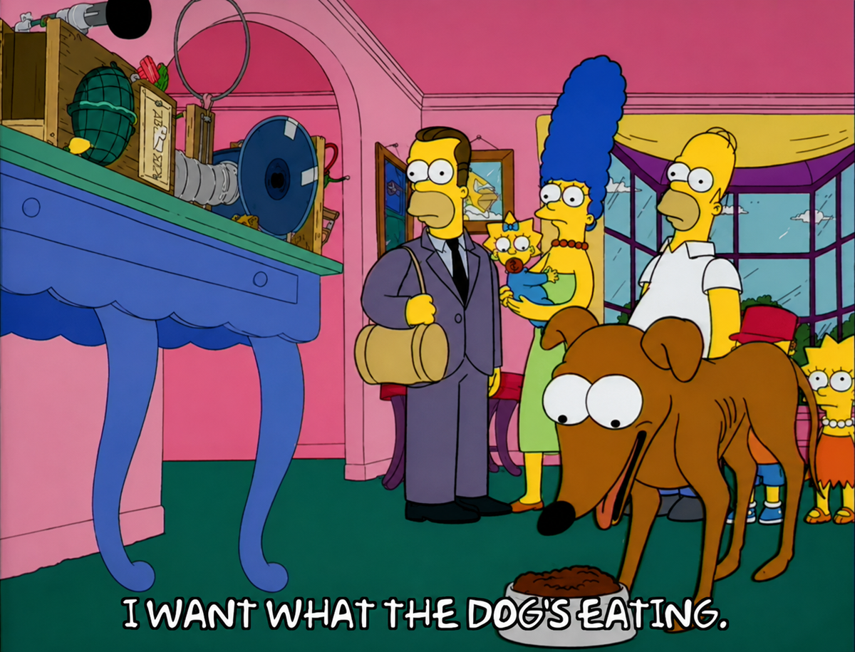 Bart, Marge, and Homer Simpson stand with a suited man in the living room, while their dog eats from a bowl. Subtitles read: "I WANT WHAT THE DOG'S EATING.