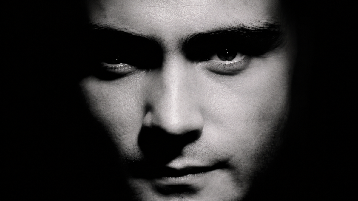 A close-up black and white photo of a man's face, half in shadow, highlighting his intense gaze and facial features with dramatic lighting.