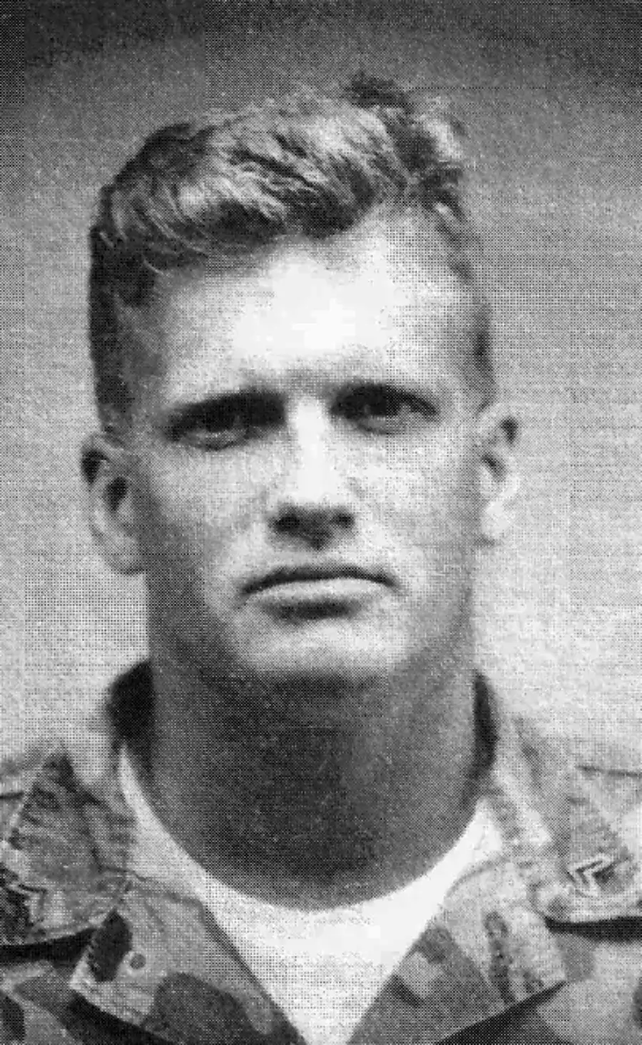 Black and white portrait of a young man in military uniform, looking directly at the camera with a neutral expression.