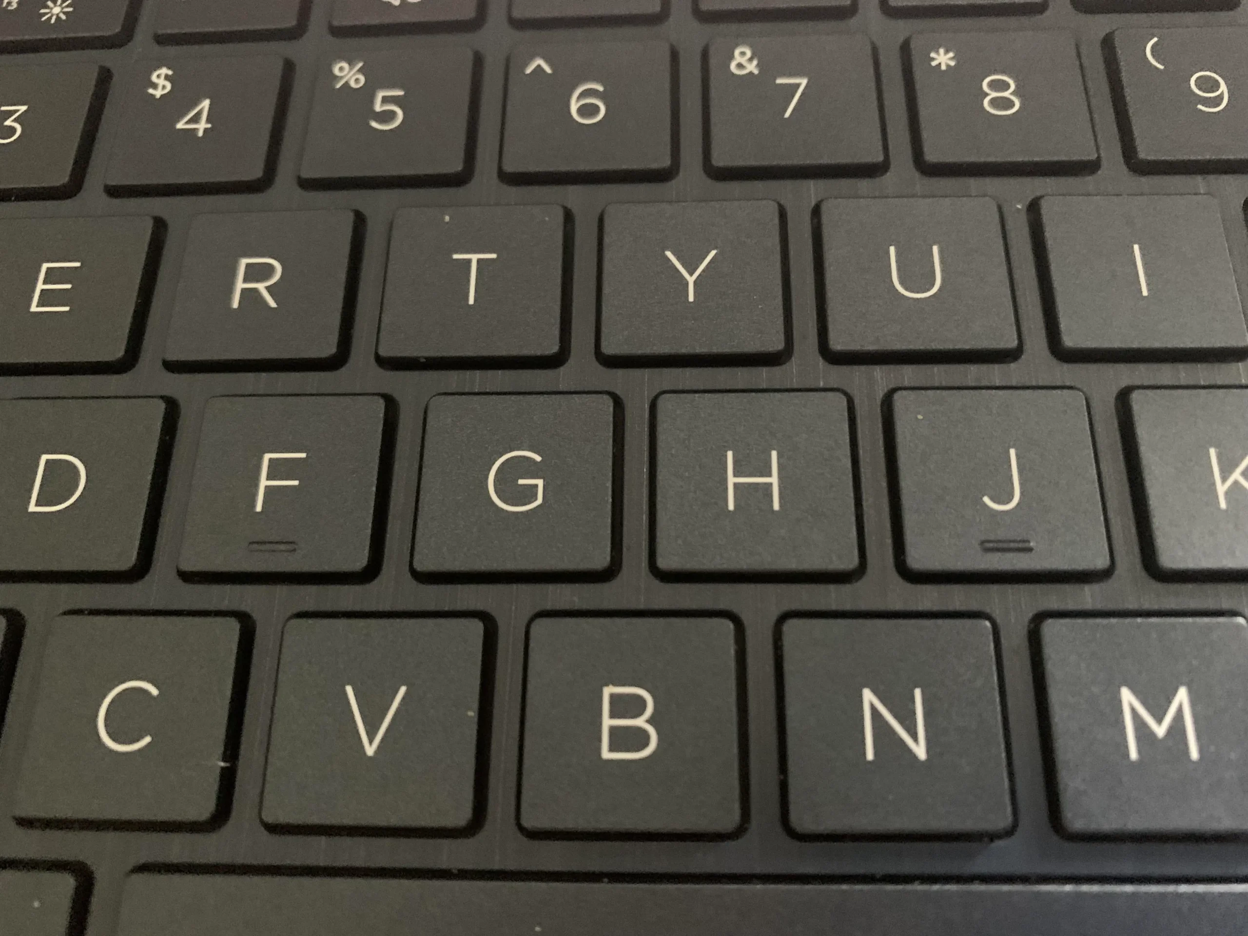 Close-up of a black computer keyboard showing the keys: E, R, T, Y, U, I, F, G, H, J, K, C, V, B, N, and M. The letters and symbols are printed in white.