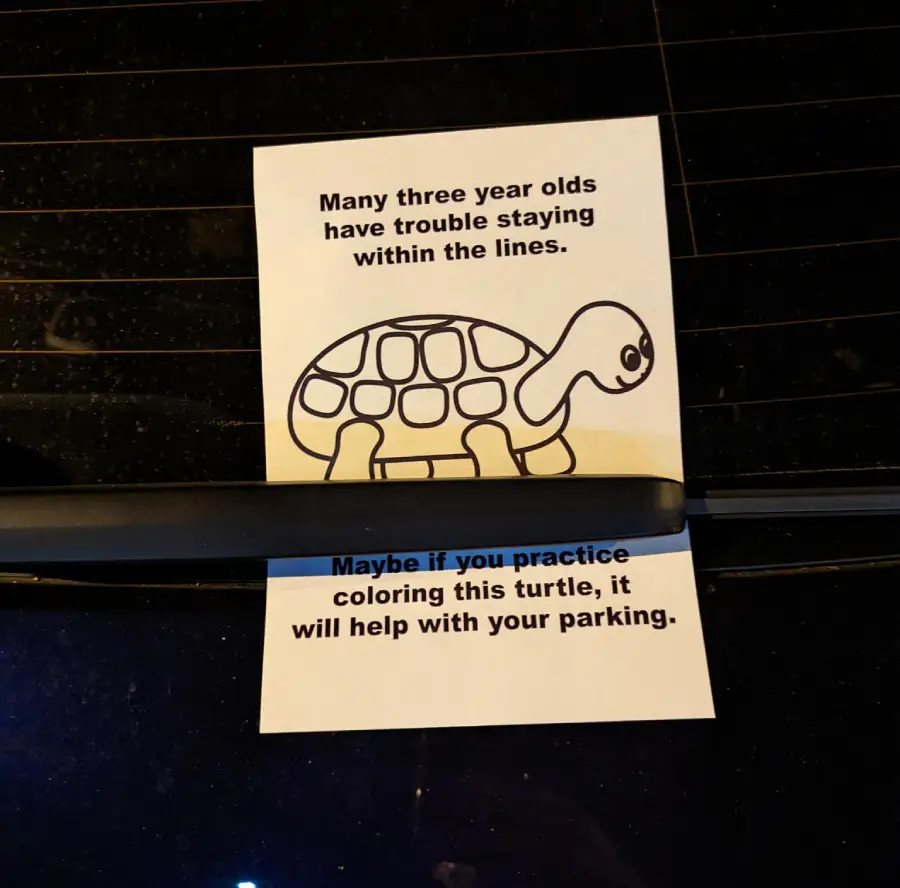 A paper with a turtle coloring page is placed under a car wiper. The note says, “Many three year olds have trouble staying within the lines. Maybe if you practice coloring this turtle, it will help with your parking.”