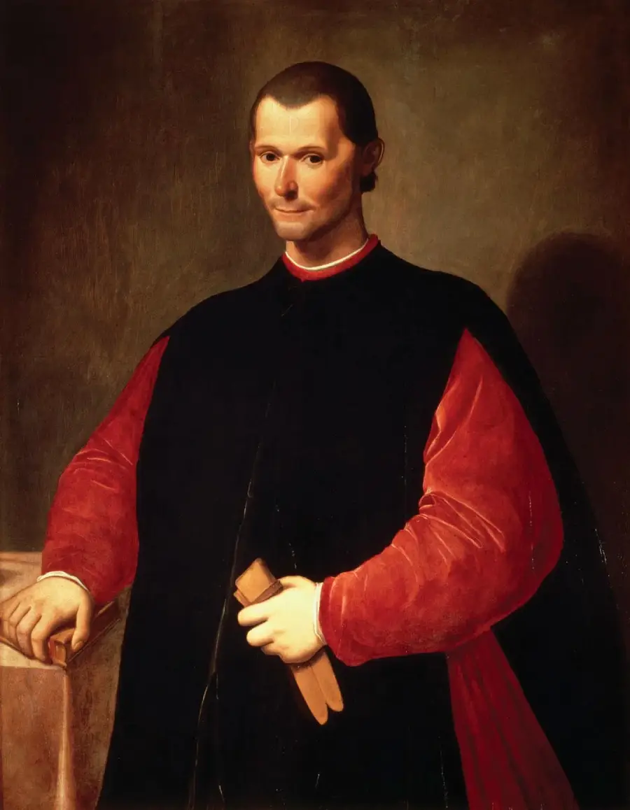 A man in Renaissance clothing with a black cloak and red sleeves stands beside a table, holding a small book, looking directly at the viewer against a dark background.