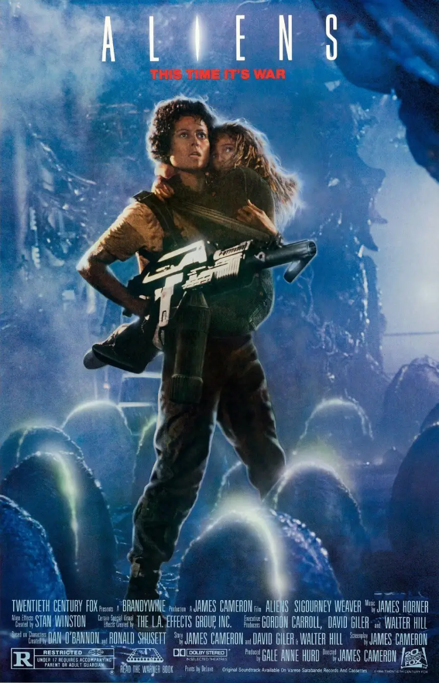 A woman holding a child and a large gun stands in a dark, alien environment with the word “ALIENS” above her and film credits below; tagline reads, “This Time It’s War.”