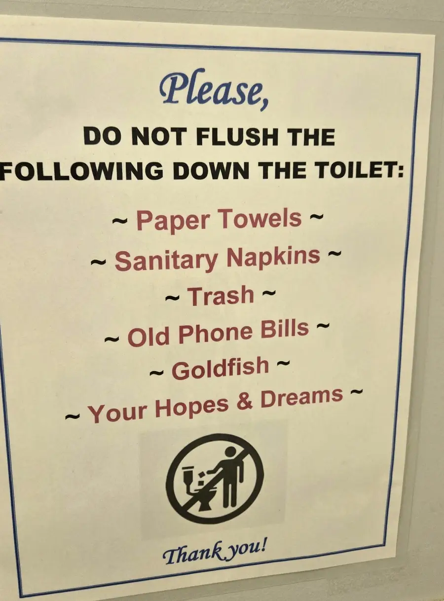 A sign on a wall lists items not to flush down the toilet, including paper towels, sanitary napkins, trash, old phone bills, goldfish, and "your hopes & dreams," with a small illustration and the word "Thank you!