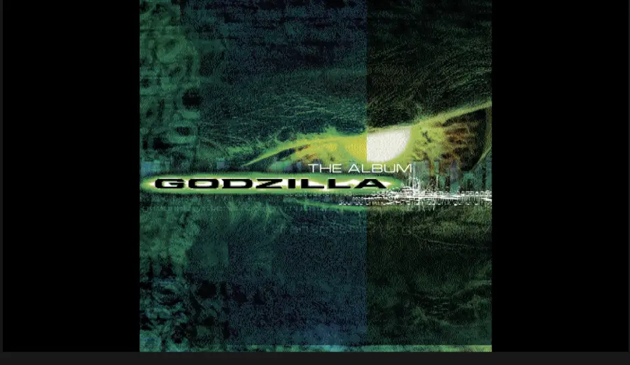 Green and black album cover with a reptilian eye in the center. Text reads "THE ALBUM" above "GODZILLA" in bold white letters, referencing the movie soundtrack. Abstract textures fill the background.
