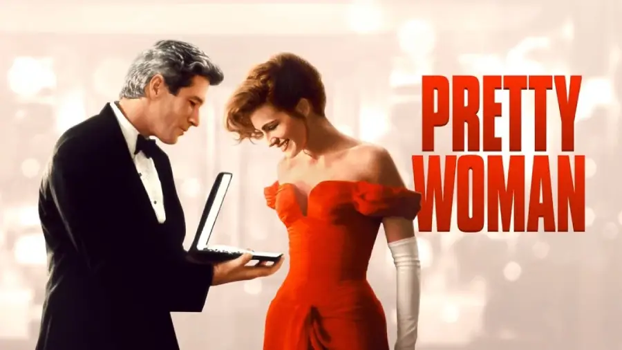 A man in a tuxedo presents a necklace to a woman in a red dress and white gloves. Both are smiling. The words "PRETTY WOMAN" appear in large red letters on the right.