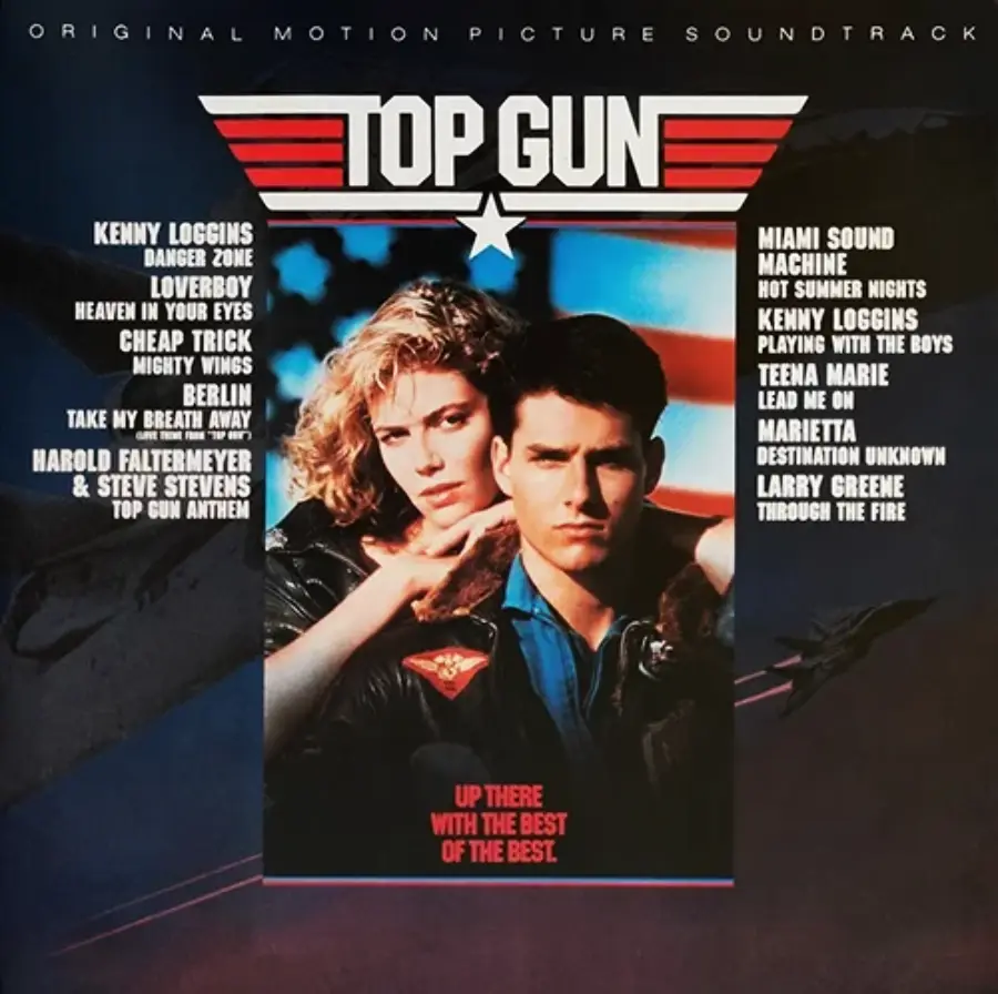 Cover art for the "Top Gun" soundtrack featuring a woman and man in front of an American flag, with a list of artists and songs on either side, and the "Top Gun" logo above them.