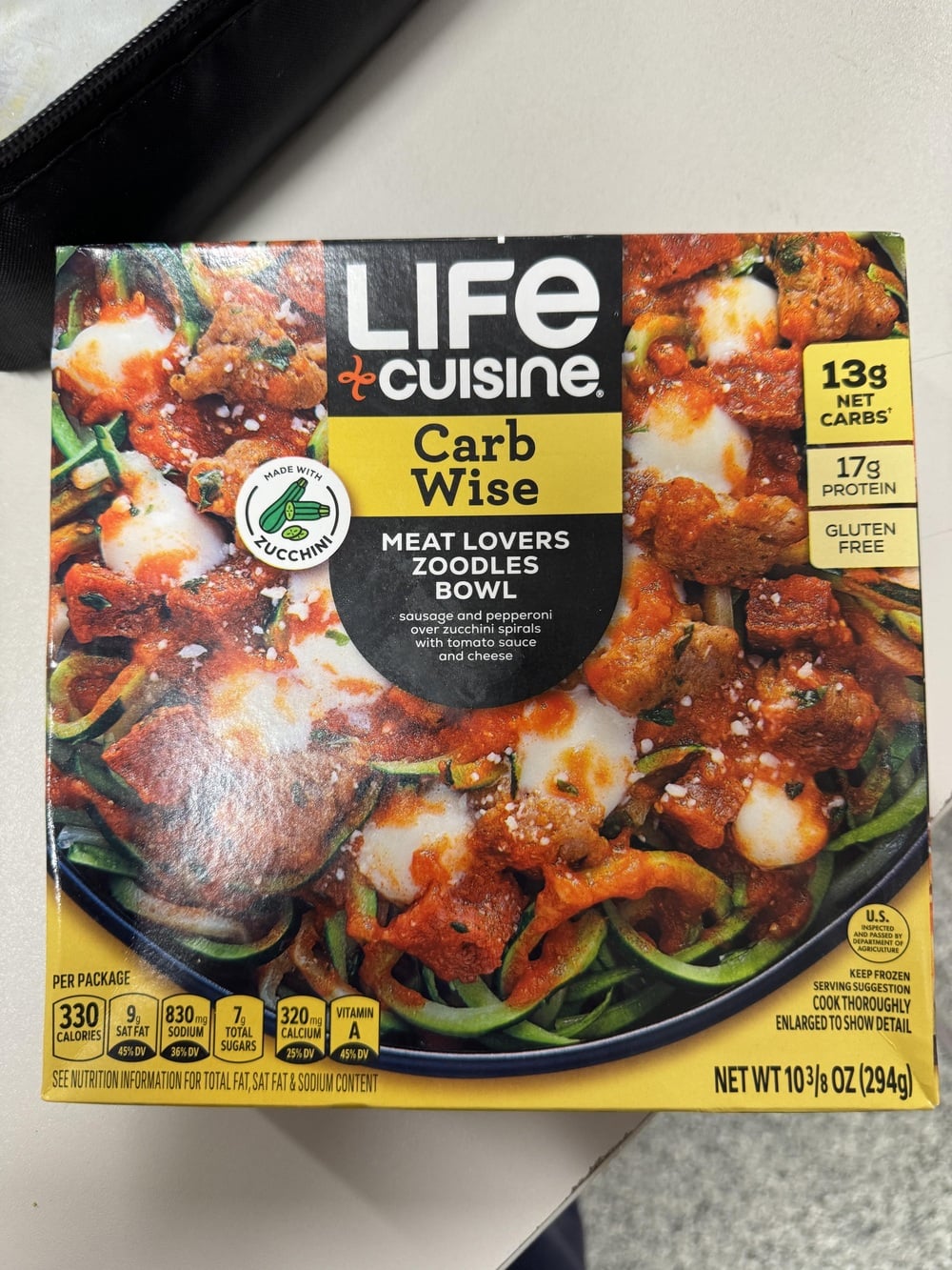 A Life Cuisine Carb Wise Meat Lovers Zoodles Bowl frozen meal featuring sausage and pepperoni over zucchini spirals, shown in its packaging with nutrition info and product details.