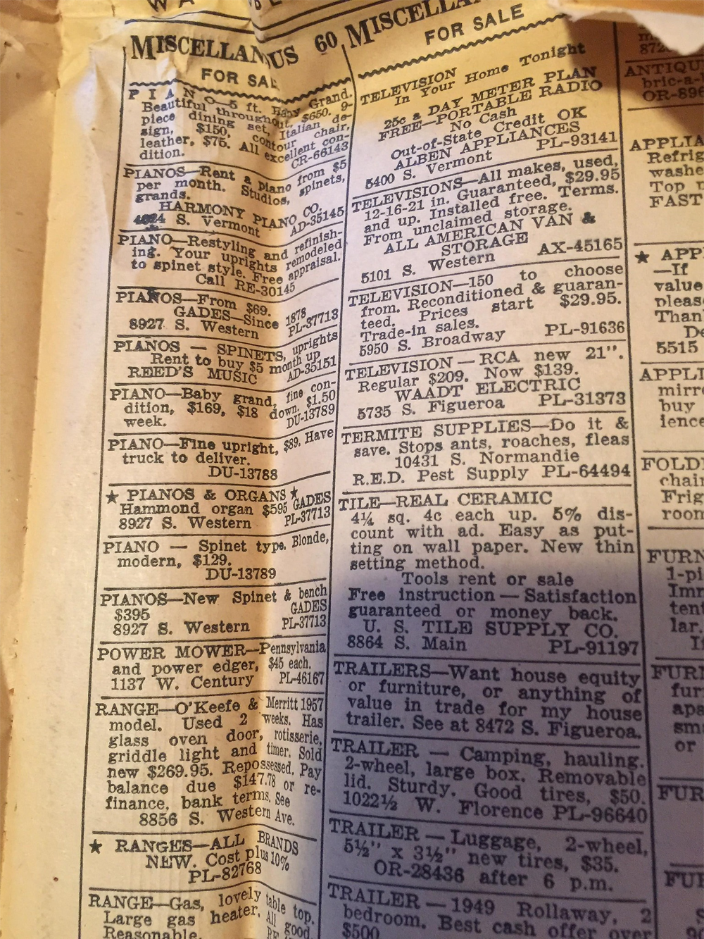 A close-up of a vintage newspaper classified ads page showing items for sale, including pianos, ranges, and radios, with yellowing and worn paper edges visible.