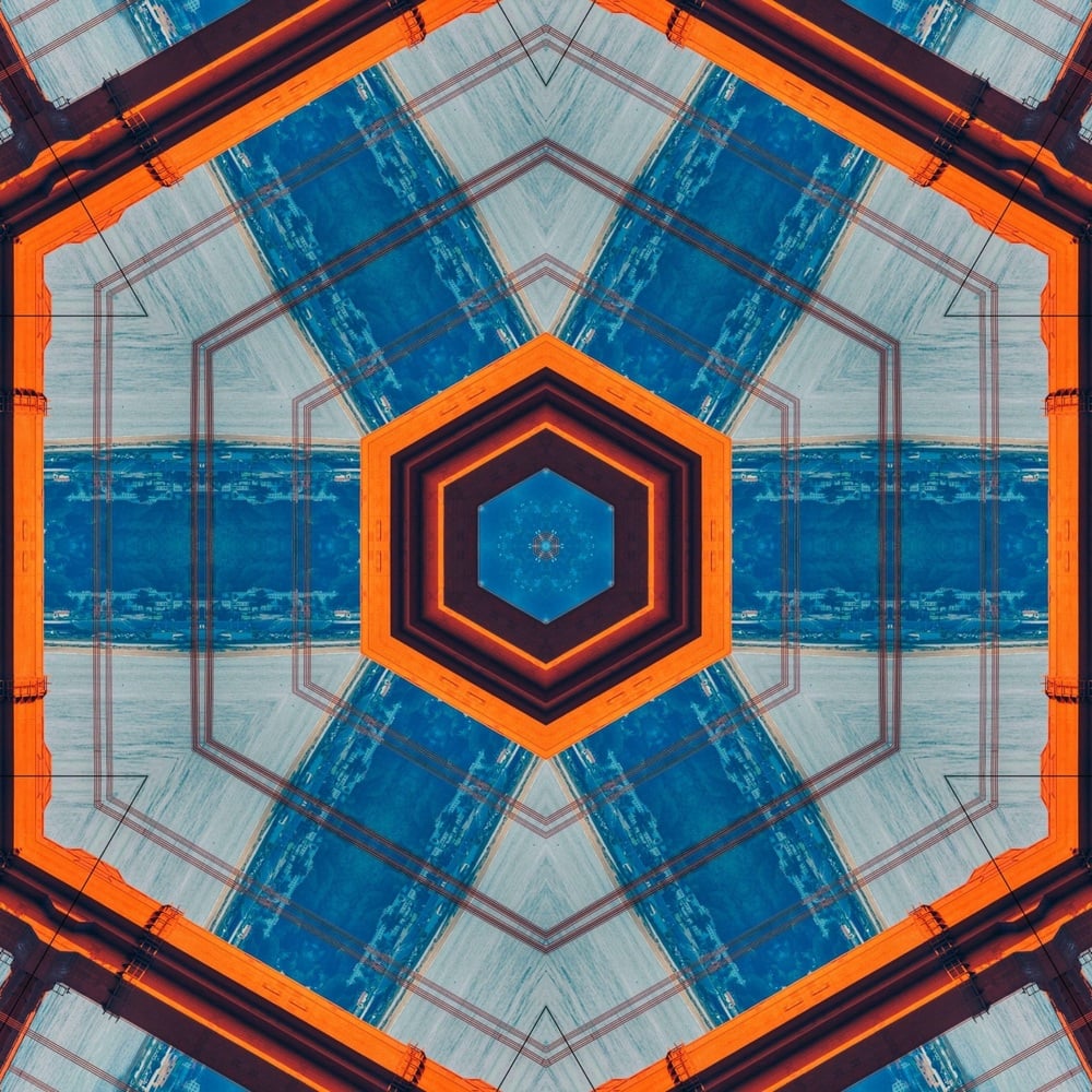 Abstract geometric pattern with a central hexagon, bold orange outlines, and intersecting blue and gray lines creating a symmetrical, kaleidoscopic design.
