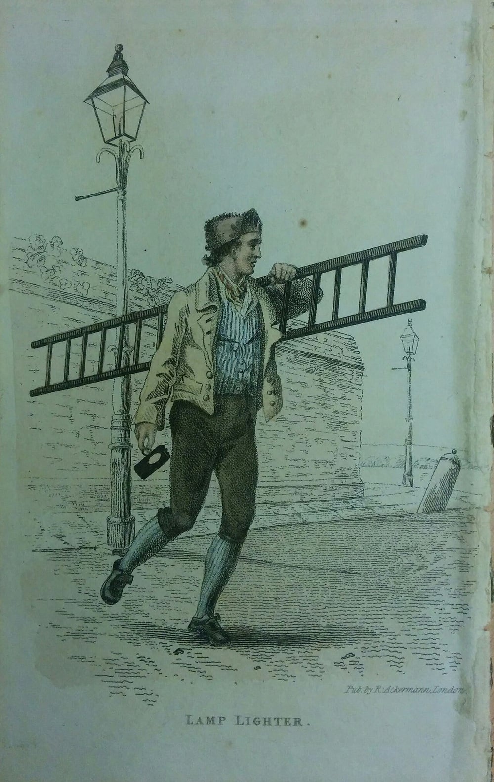 A man carries a ladder and a lantern, walking towards a streetlamp on a cobblestone road. He wears a cap, jacket, and striped vest. Another streetlamp is visible in the background.