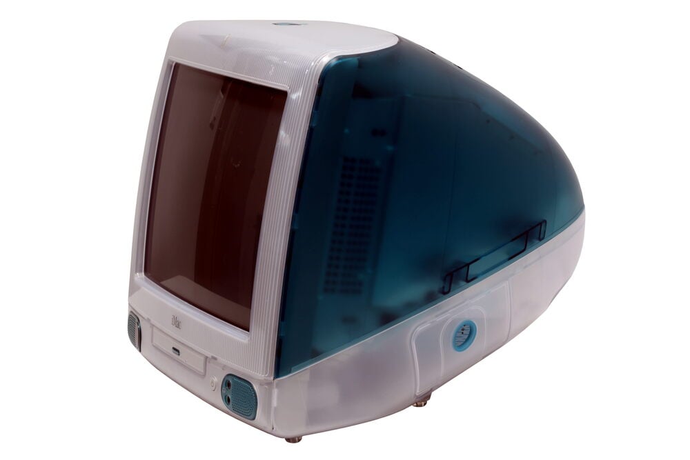 A teal-and-white Apple iMac G3 desktop computer with a curved, translucent plastic casing and a built-in CRT monitor.