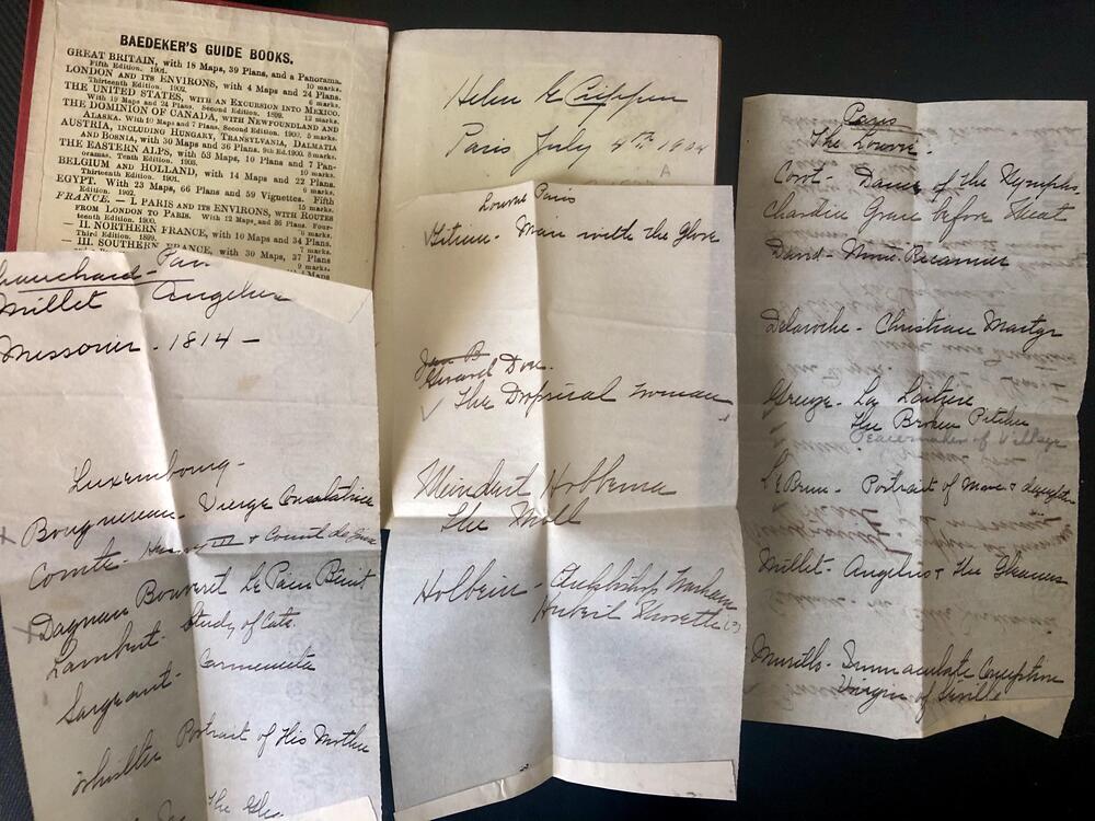 Four handwritten letters on white paper are spread out beside an open book showing a Baedeker’s Guide Book notice. The letters appear old, featuring cursive writing with visible creases from folding.
