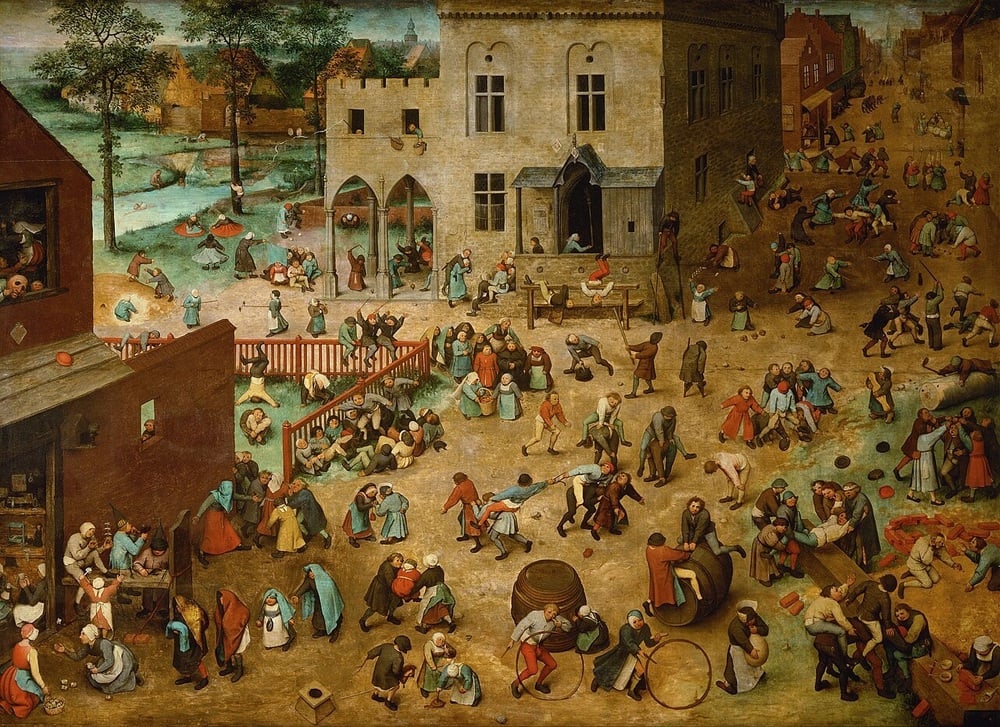 A lively medieval town square filled with children and adults playing various games, surrounded by buildings, trees, and water in the background. The scene is crowded and bustling with activity.