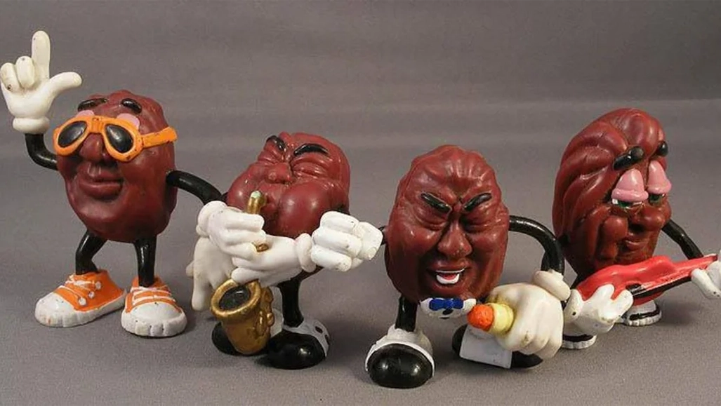 Four anthropomorphic raisins with faces and limbs, wearing sunglasses and shoes, are posed as a band; one played saxophone, one sang, and one played guitar.