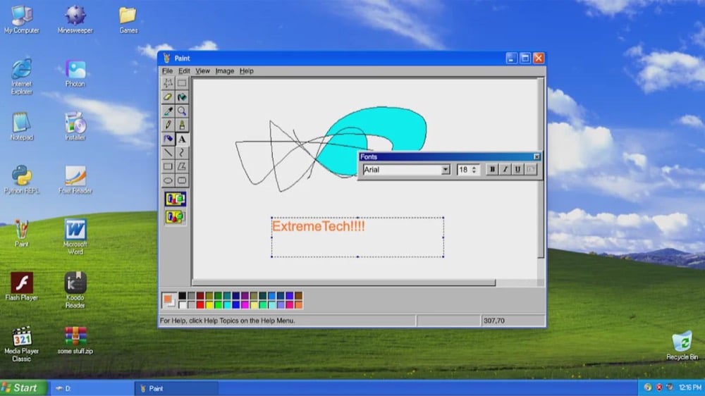 A Windows XP desktop with MS Paint open, showing colorful scribbles and the text “ExtremeTech!!!” in orange. Classic icons and the green Start menu are visible on the desktop.