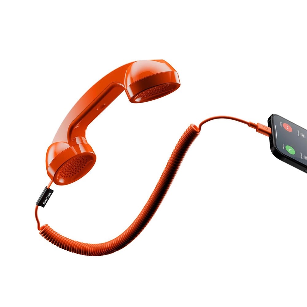 A classic red corded phone handset is connected by a coiled cable to a modern smartphone, which displays an incoming call screen.