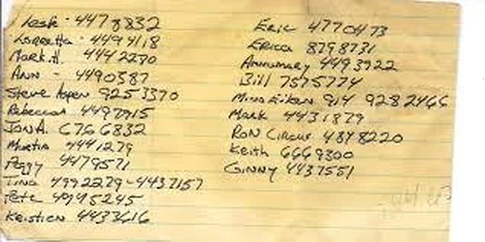 A handwritten list of names with phone numbers on a lined yellow paper, showing first names and various seven-digit numbers in columns, written in pen with some areas smudged.