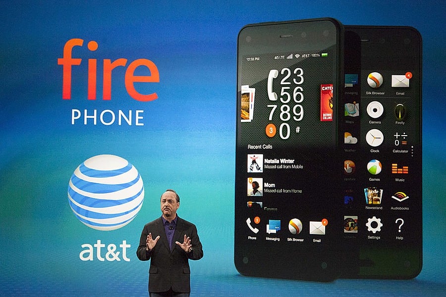 A man stands on stage in front of a large Fire Phone and AT&T logo, presenting the smartphone’s interface and features on a blue background.