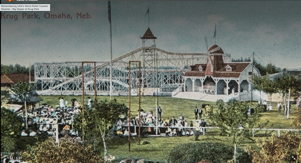 A vintage postcard shows Krug Park in Omaha, Nebraska, with crowds gathered on the lawn, a white wooden roller coaster, and a large pavilion with a pointed red roof in the background.