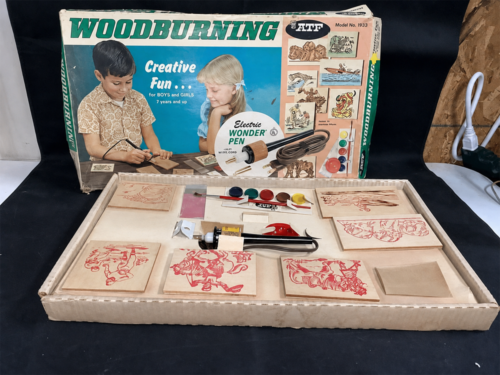 Vintage woodburning kit with a box showing two children using the tool. Inside the box are wood pieces with designs, a woodburning pen, paint pots, tools, and instructions. The kit is labeled for ages 7 and up.