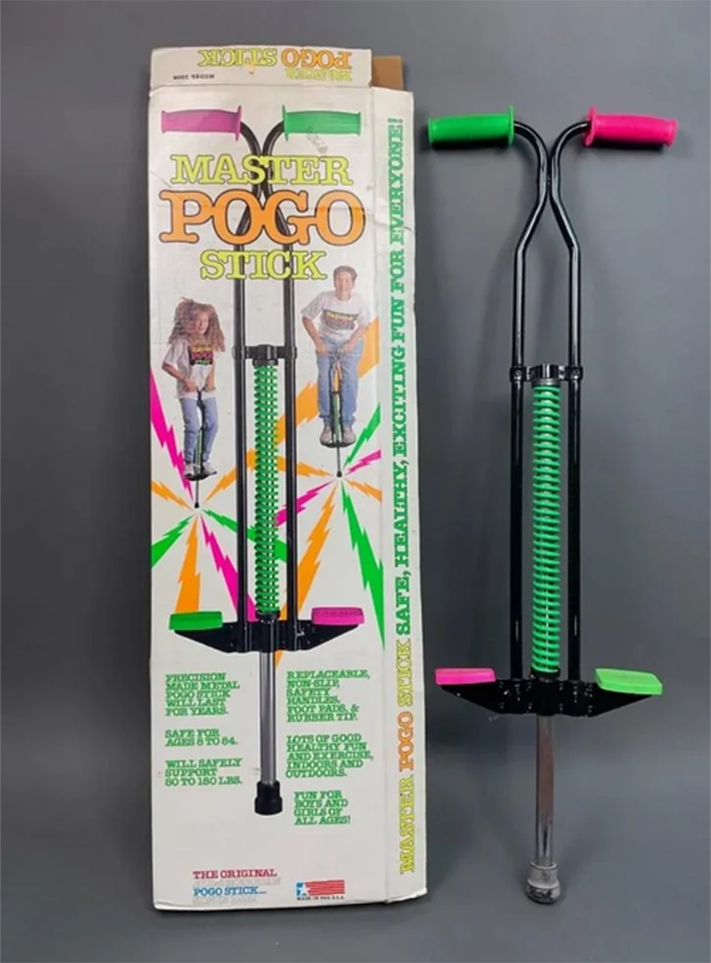 A black and green pogo stick stands beside its colorful box, which displays photos of children using the pogo stick and includes text highlighting its features and safety.