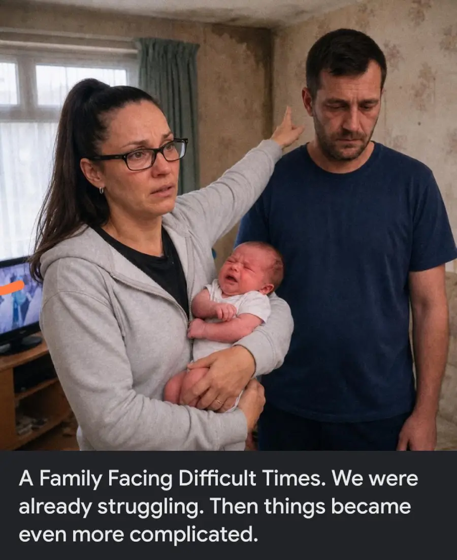A woman holding a crying baby points at a wall while a man stands beside her, both looking upset, in a modest room with peeling wallpaper.