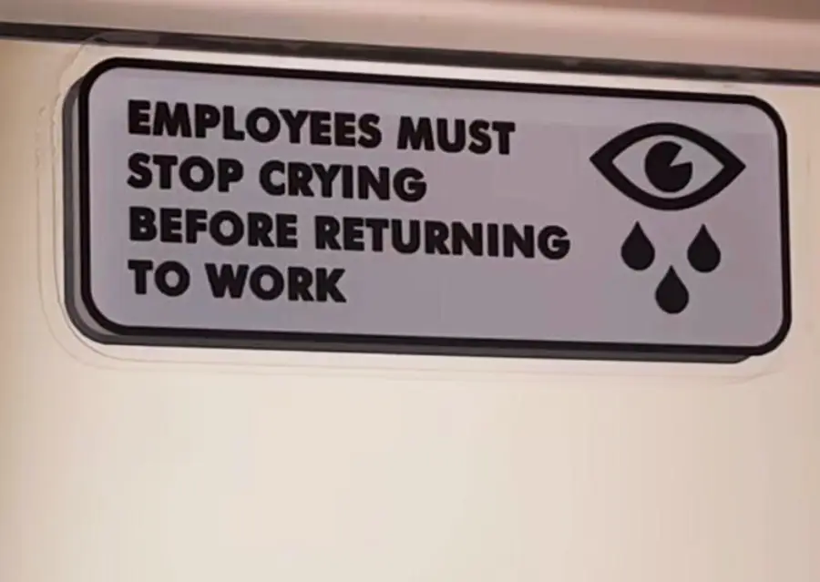 A sign reads “Employees must stop crying before returning to work” with an eye and three teardrops graphic beside the text.