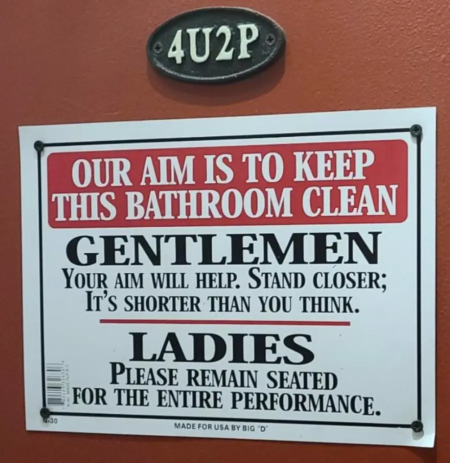 A humorous bathroom sign urges men to stand closer and women to stay seated for cleanliness; a small plaque above reads “4U2P.”