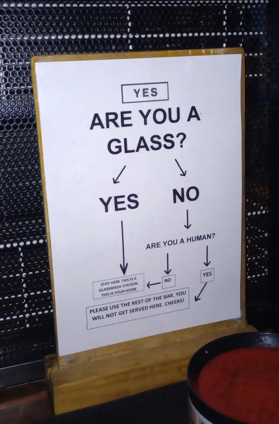 A humorous sign asks, “Are you a glass?” with flowchart arrows leading to instructions for glasses and humans in a bar, indicating where to stay or be served.