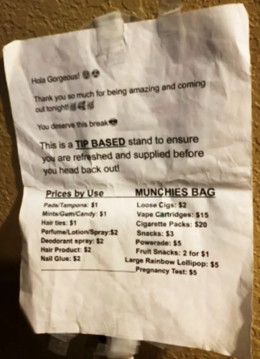 A wrinkled paper sign lists prices for various items like pads, snacks, and vape cartridges, stating it’s a tip-based stand for refreshment. The message thanks users and encourages tipping before they head back out.
