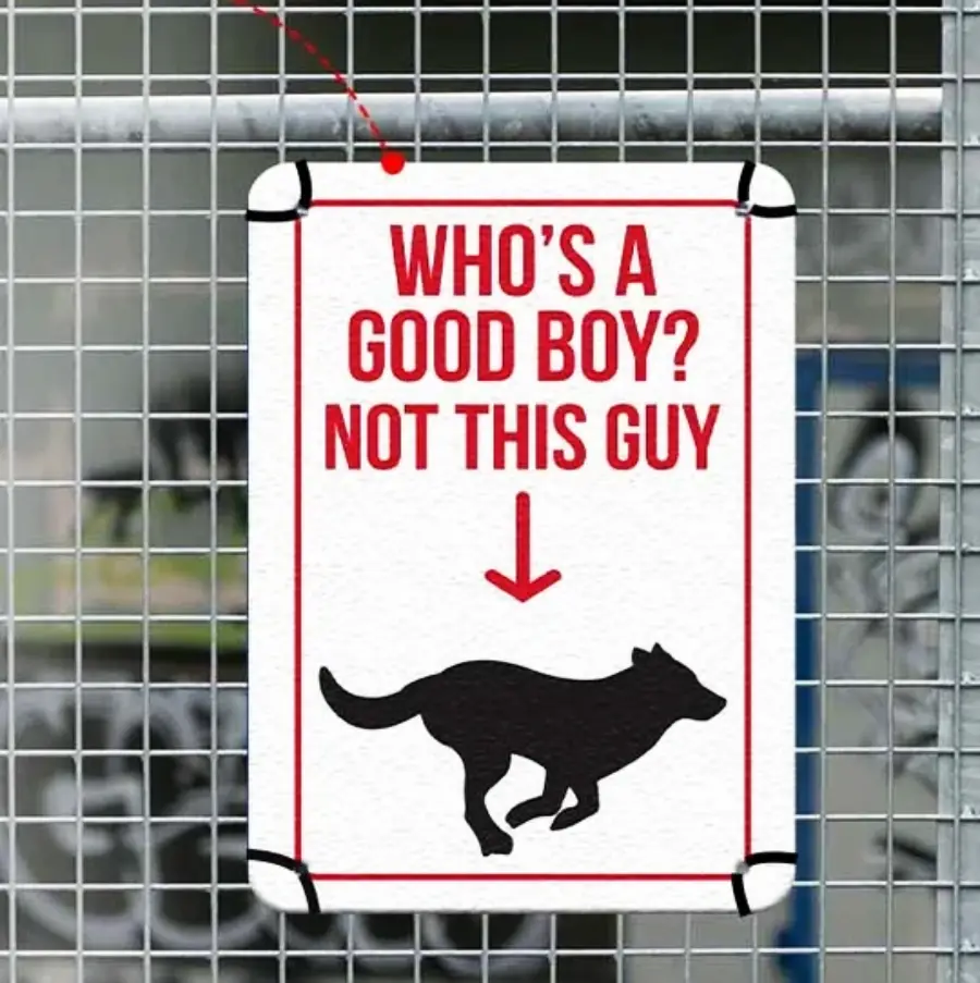 A sign on a fence reads, “WHO’S A GOOD BOY? NOT THIS GUY” with a downward arrow pointing to a silhouette of a dog.