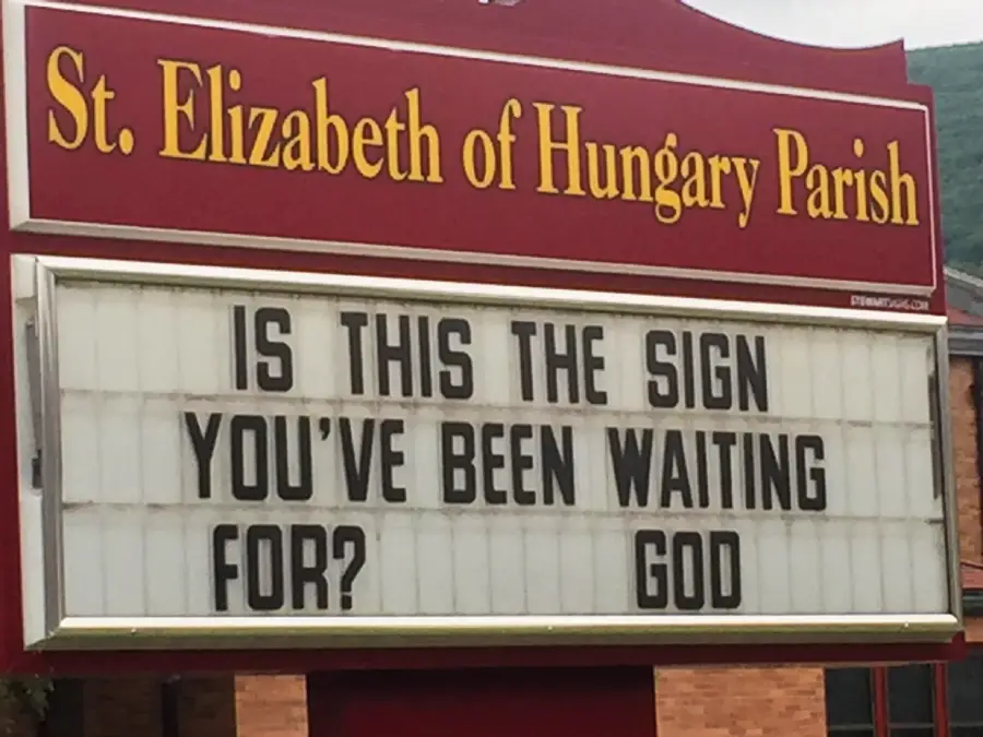 A church sign reads: “IS THIS THE SIGN YOU’VE BEEN WAITING FOR? GOD” beneath “St. Elizabeth of Hungary Parish” on a red background.