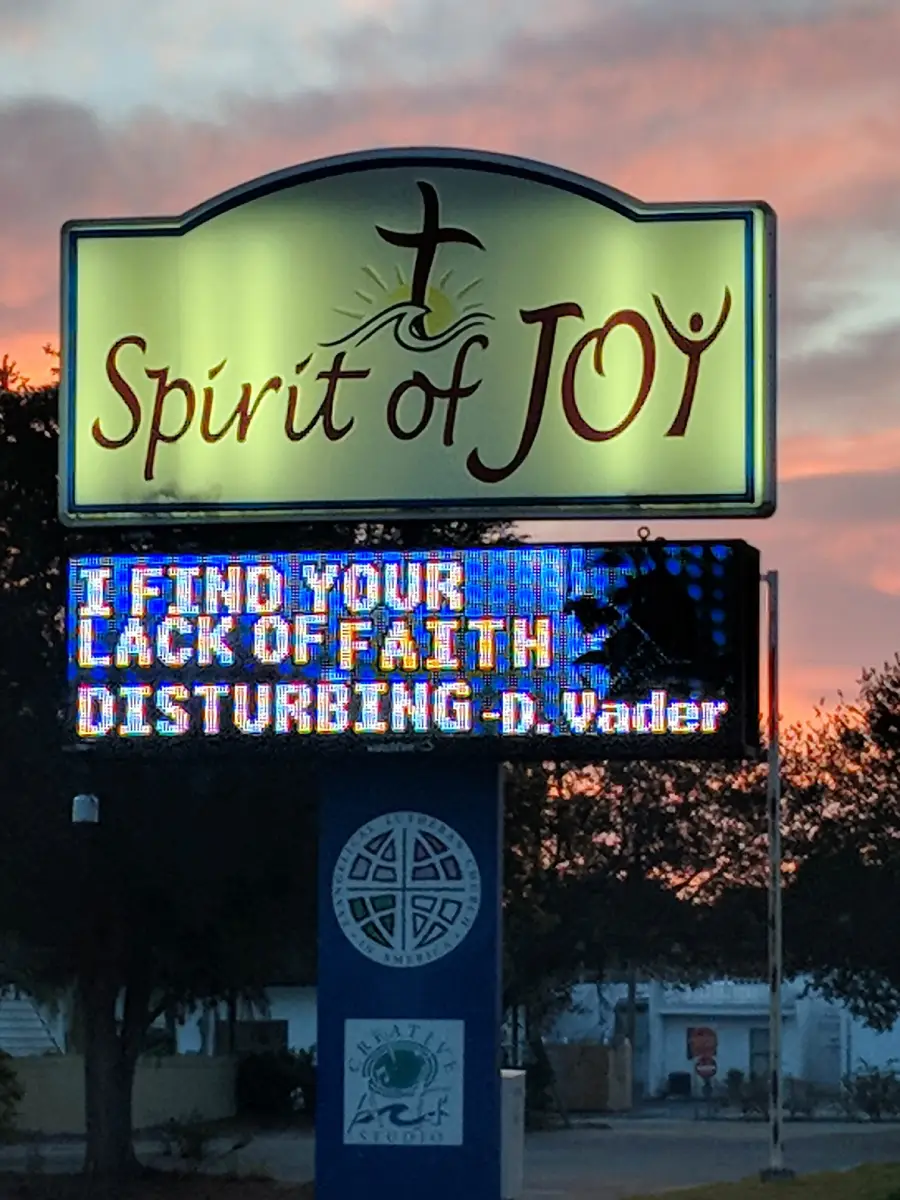 A church sign reads “Spirit of Joy” above, with a digital message below stating “I FIND YOUR LACK OF FAITH DISTURBING - D. Vader” at sunset.