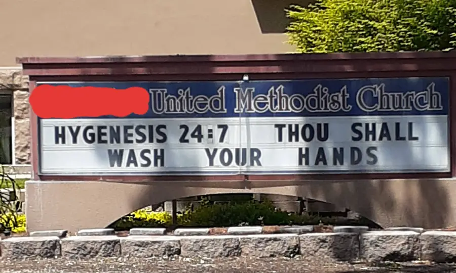 A church sign reads: “Hygensis 24:7 Thou shall wash your hands.” Part of the church name is redacted. The sign humorously mimics a Bible verse to encourage hand washing.