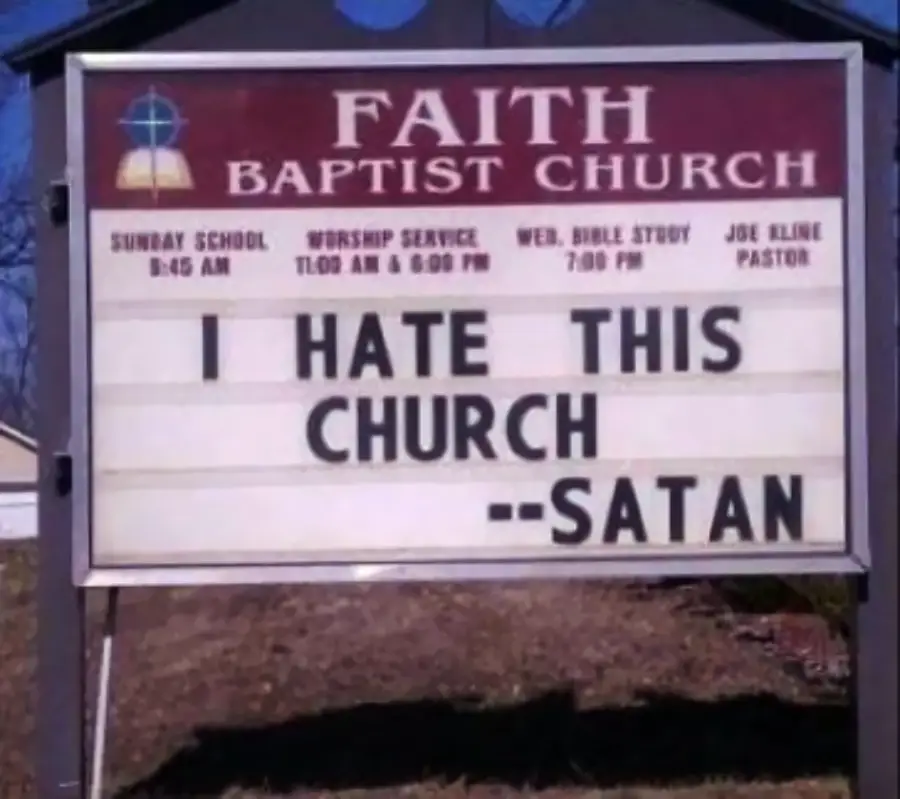 A church sign reads: “I HATE THIS CHURCH --SATAN” under the heading “FAITH BAPTIST CHURCH”. Service times and the pastor’s name are also listed above.