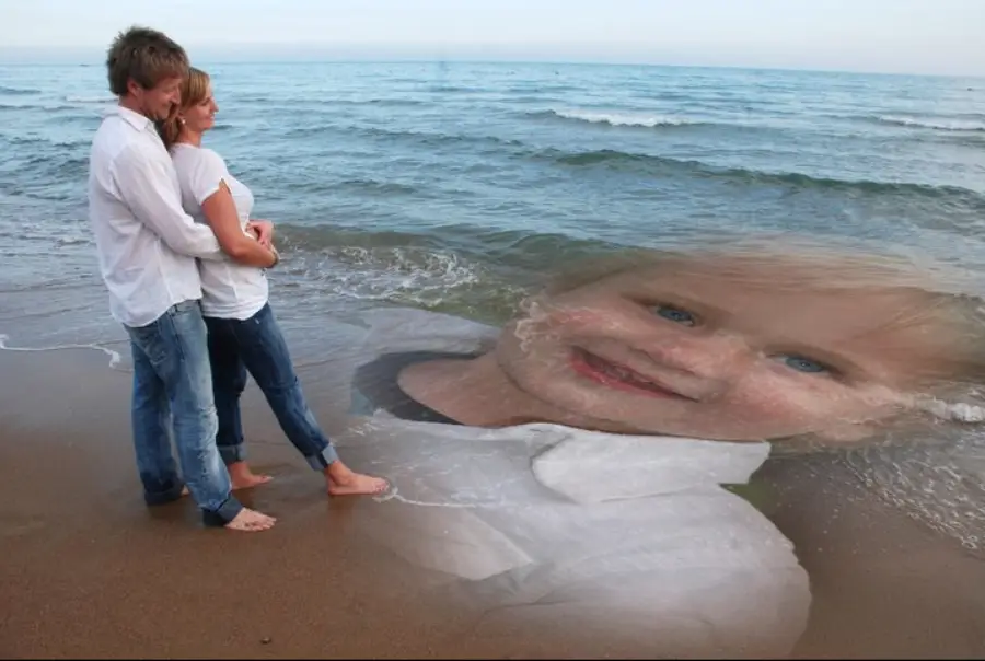 A couple stands on a beach, embracing, while a large, semi-transparent image of a smiling child is superimposed over the waves and sand.