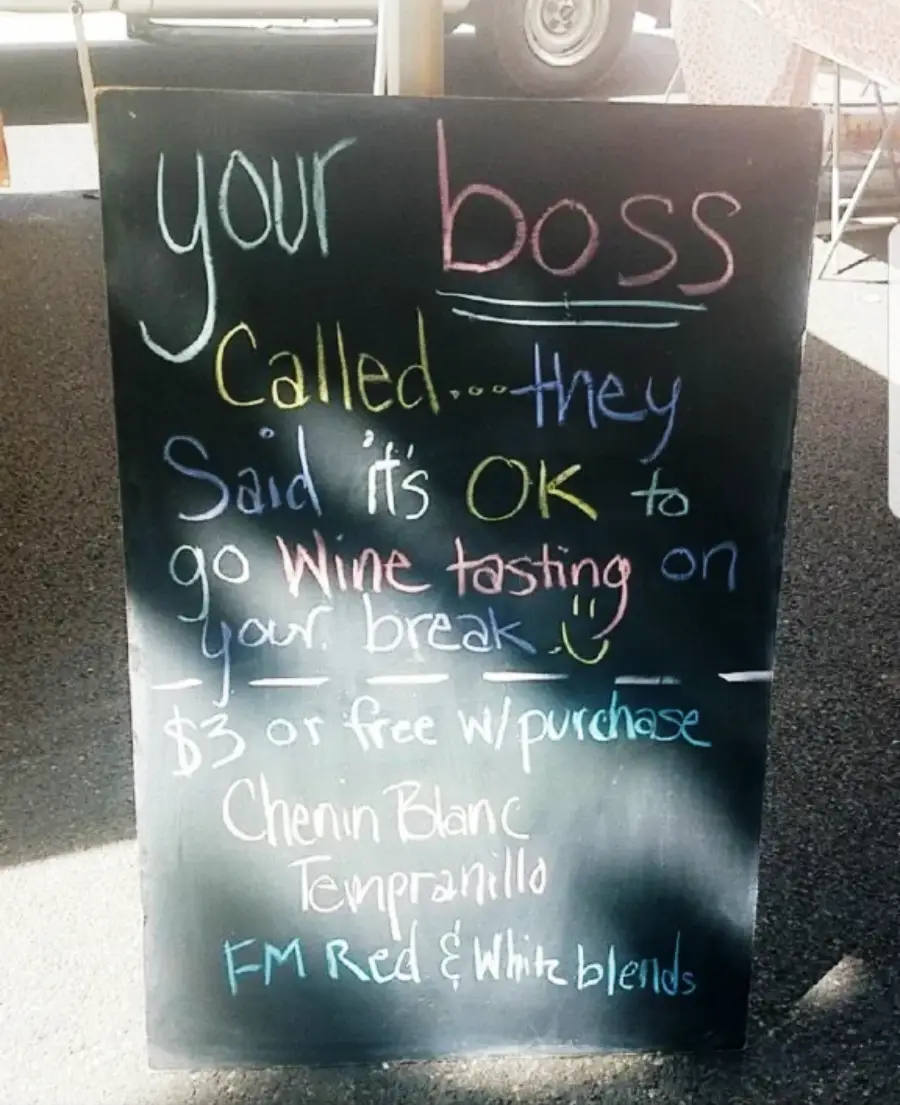 A chalkboard sign humorously says your boss approves wine tasting on your break, with details on $3 tastings or free with purchase, and lists Chenin Blanc, Tempranillo, and red and white blends.