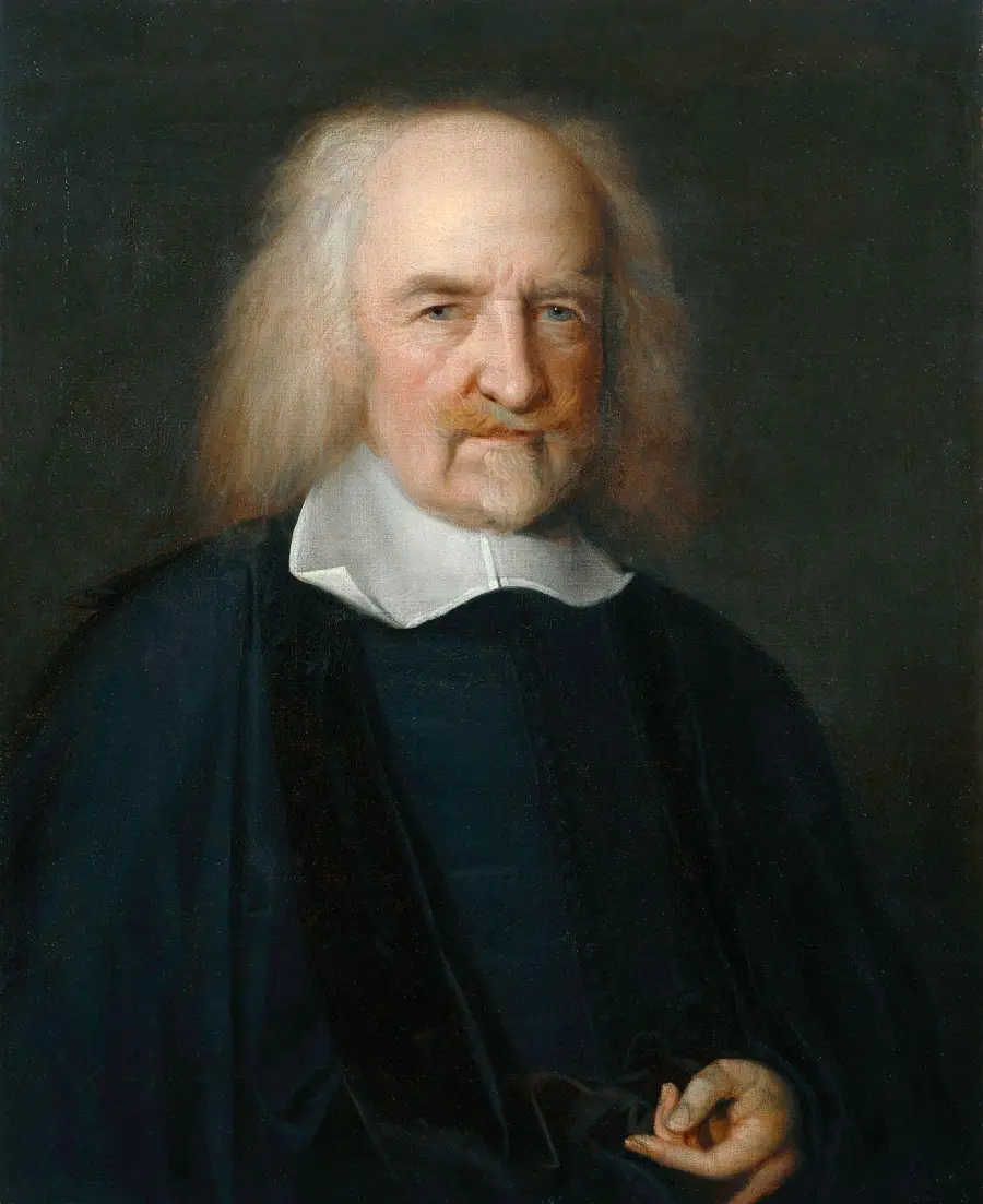 An elderly man with long white hair, wearing a dark robe and a white collar, poses against a dark background, looking slightly to the side.