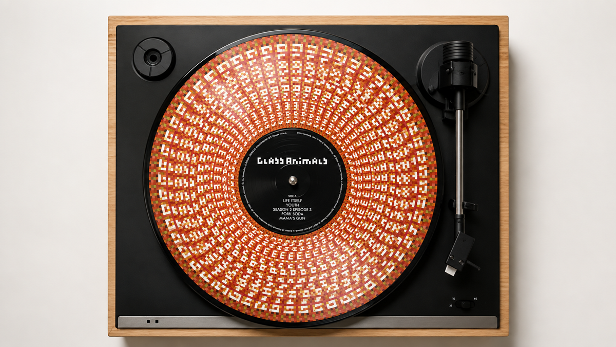 A record player with a vibrant, patterned vinyl record on its turntable. The record’s center label reads “Glass Animals.” The player has a wooden frame and a black platter with a tonearm on the right side.